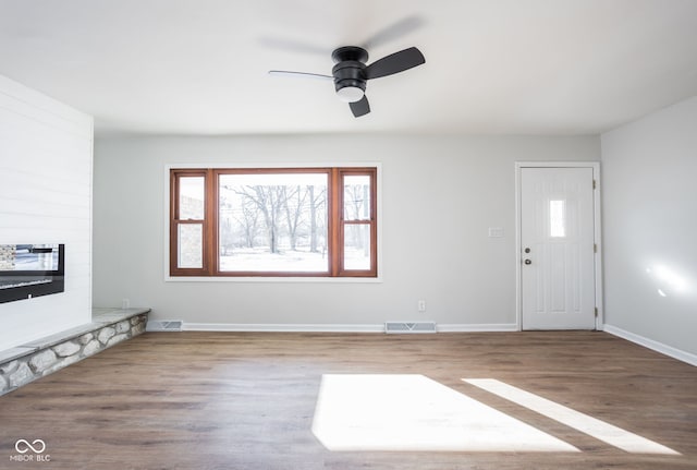 unfurnished living room featuring hardwood / wood-style flooring, ceiling fan, and a fireplace