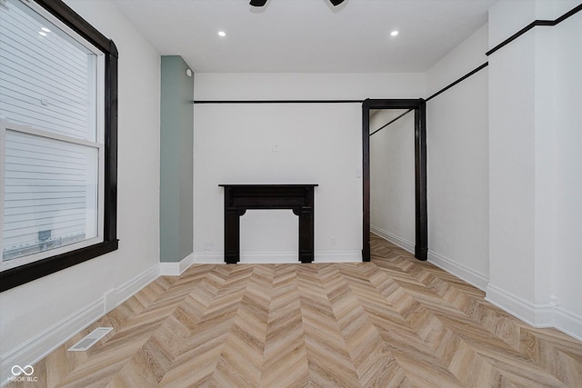 unfurnished living room featuring ceiling fan, a fireplace, and light parquet flooring