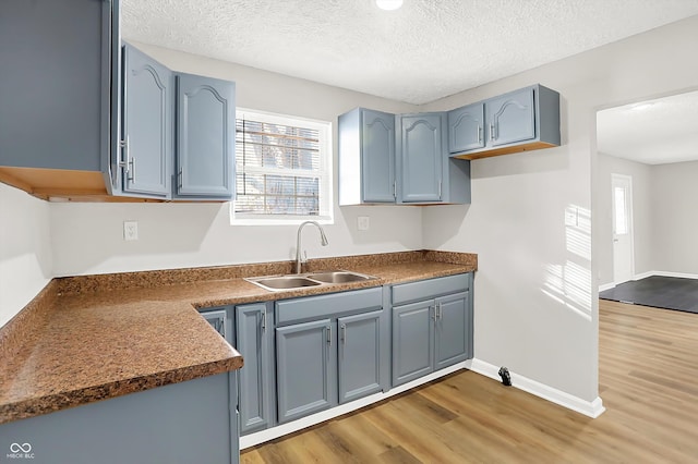 kitchen with hardwood / wood-style flooring, sink, a textured ceiling, and blue cabinets