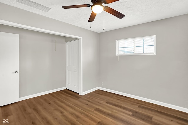 unfurnished bedroom featuring a textured ceiling, a closet, ceiling fan, and dark hardwood / wood-style flooring