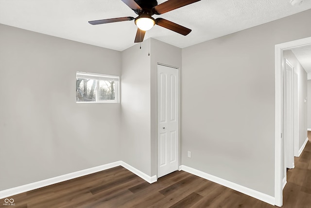 unfurnished bedroom featuring dark wood-type flooring, a textured ceiling, a closet, and ceiling fan