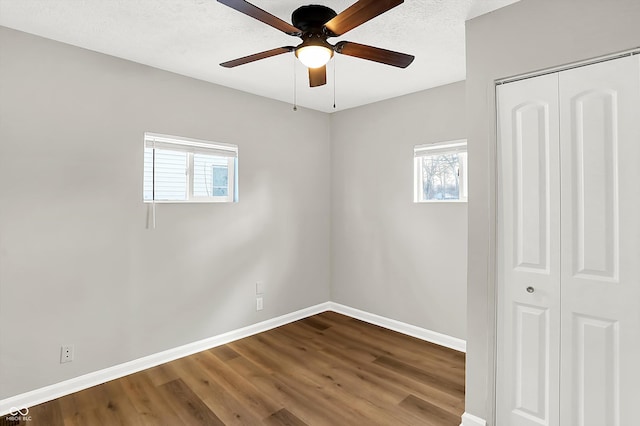 spare room featuring ceiling fan, a wealth of natural light, hardwood / wood-style floors, and a textured ceiling