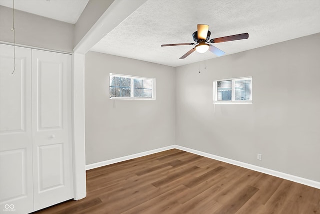 spare room with ceiling fan, dark wood-type flooring, and a textured ceiling