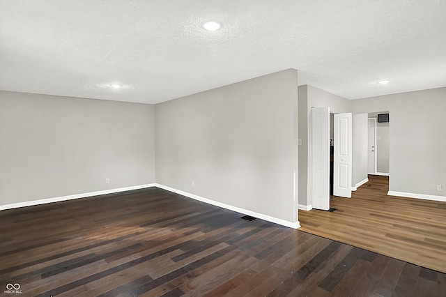 unfurnished room with a textured ceiling and dark hardwood / wood-style floors