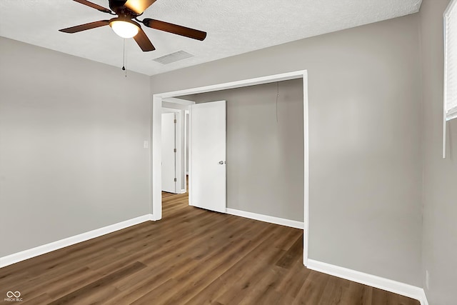 unfurnished bedroom featuring dark wood-type flooring, a textured ceiling, a closet, and ceiling fan