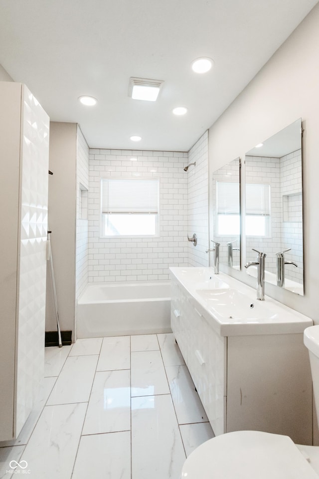 full bathroom featuring vanity, tiled shower / bath, and toilet