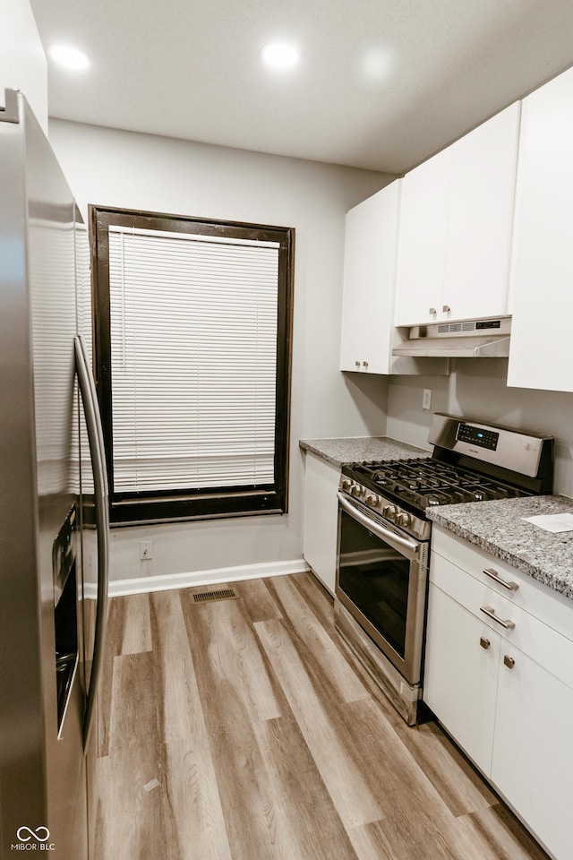 kitchen with white cabinetry, appliances with stainless steel finishes, light wood-type flooring, and light stone counters