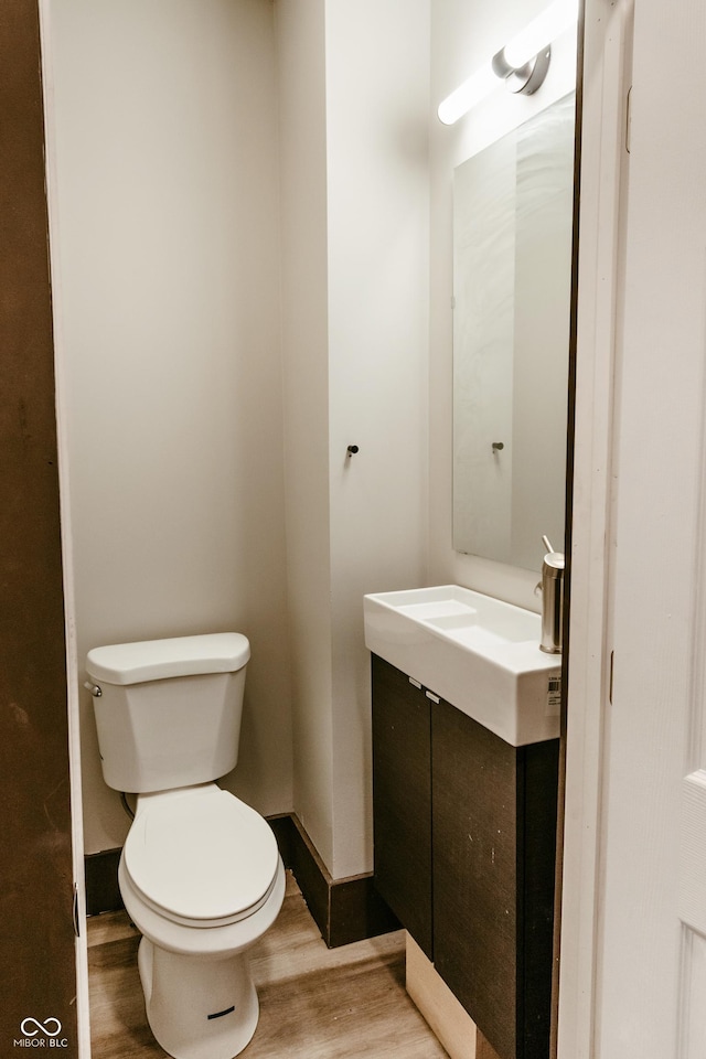 bathroom with hardwood / wood-style flooring, vanity, and toilet