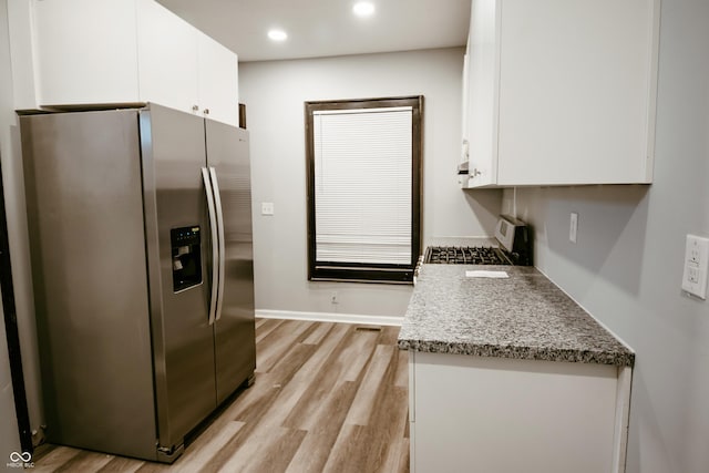 kitchen with white cabinetry, range, stainless steel refrigerator with ice dispenser, light stone countertops, and light hardwood / wood-style flooring