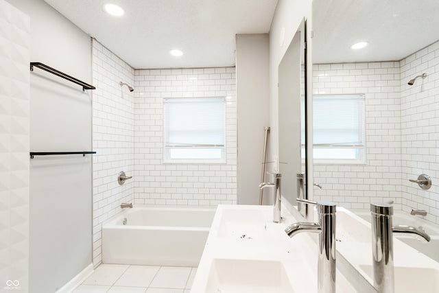 bathroom with tile patterned flooring, tiled shower / bath combo, plenty of natural light, and a textured ceiling