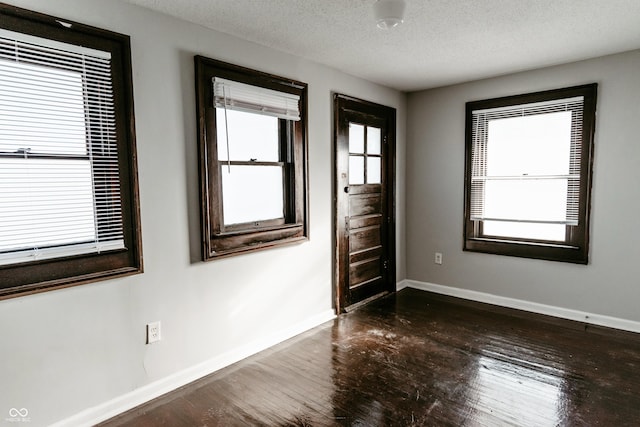 empty room featuring dark hardwood / wood-style floors and a textured ceiling