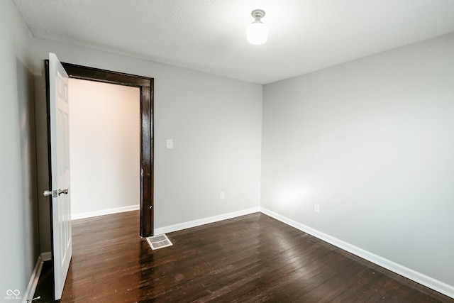 spare room featuring dark hardwood / wood-style flooring and a textured ceiling