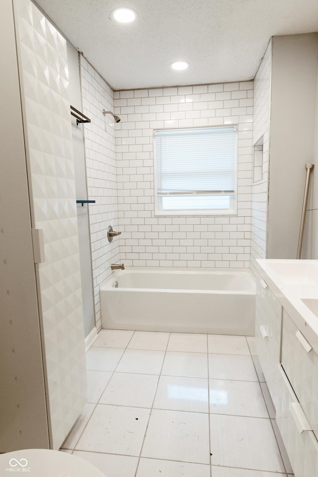 bathroom with vanity, tiled shower / bath combo, tile patterned floors, and a textured ceiling