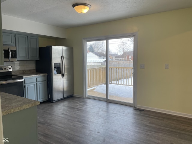 kitchen featuring appliances with stainless steel finishes, a textured ceiling, backsplash, dark hardwood / wood-style floors, and gray cabinets