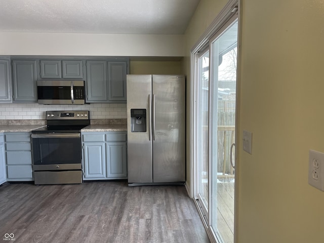 kitchen featuring a textured ceiling, gray cabinetry, backsplash, stainless steel appliances, and dark hardwood / wood-style floors