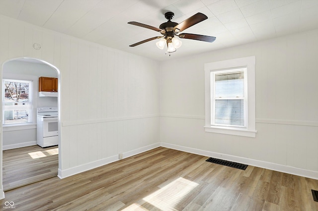 empty room with a wealth of natural light, ceiling fan, and light hardwood / wood-style flooring