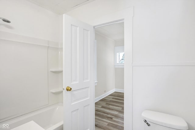 bathroom featuring bathing tub / shower combination, hardwood / wood-style floors, and toilet