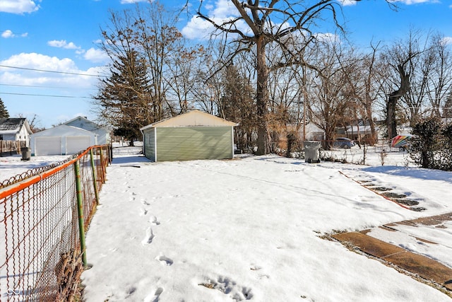 yard layered in snow with a garage and an outbuilding