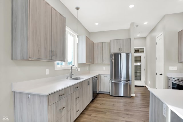 kitchen featuring stainless steel appliances, light brown cabinetry, sink, and light hardwood / wood-style flooring