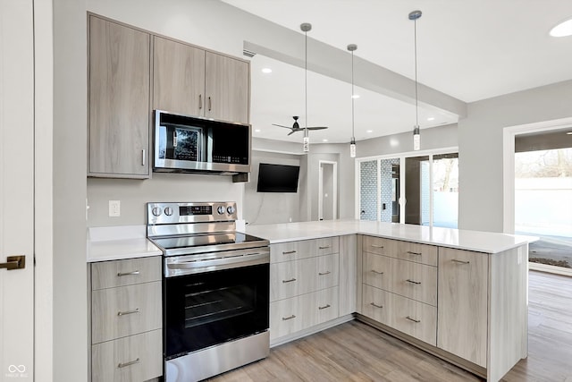 kitchen featuring appliances with stainless steel finishes, light brown cabinetry, and kitchen peninsula