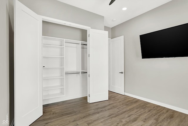 unfurnished bedroom featuring hardwood / wood-style floors, ceiling fan, and a closet