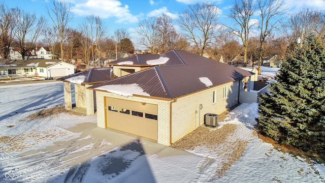 view of snowy exterior with a garage and central air condition unit