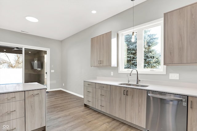 kitchen with sink, light hardwood / wood-style flooring, hanging light fixtures, light brown cabinetry, and stainless steel dishwasher