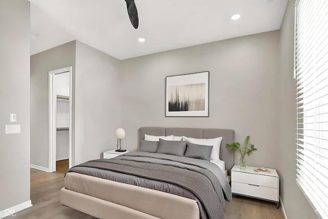 bedroom featuring hardwood / wood-style flooring, ceiling fan, a spacious closet, and a closet