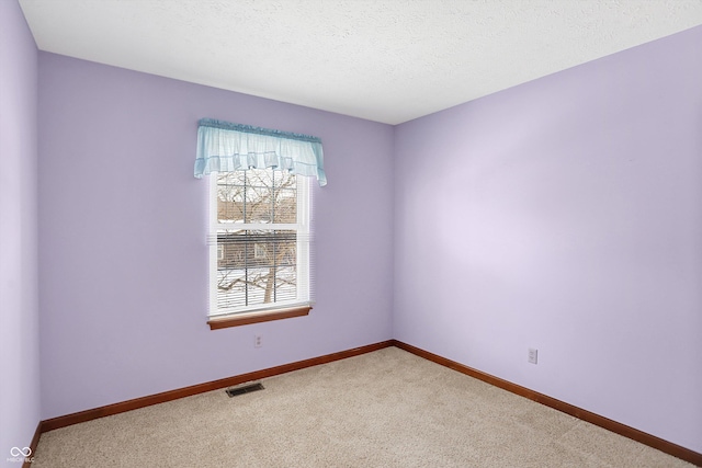 carpeted empty room featuring a textured ceiling