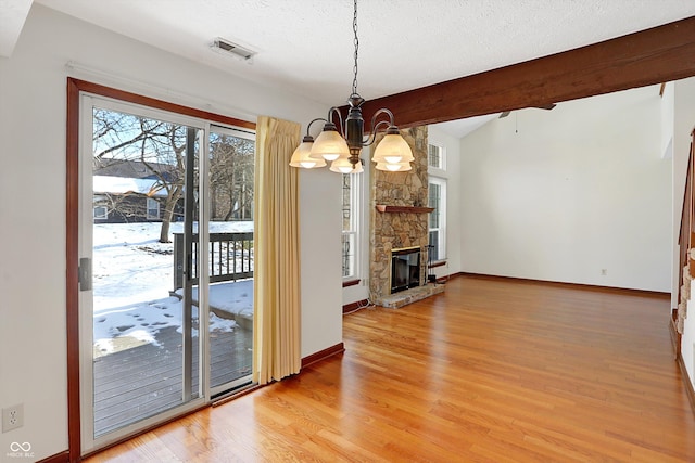 unfurnished living room featuring a fireplace, a textured ceiling, hardwood / wood-style flooring, a chandelier, and vaulted ceiling with beams