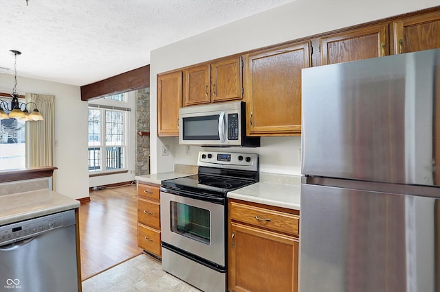 kitchen featuring stainless steel appliances, an inviting chandelier, pendant lighting, and a textured ceiling