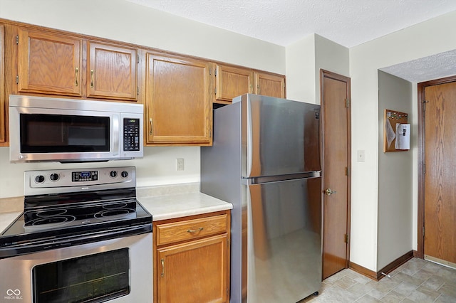 kitchen with a textured ceiling and appliances with stainless steel finishes