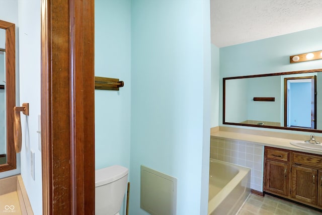 bathroom featuring a textured ceiling, toilet, vanity, and a bath