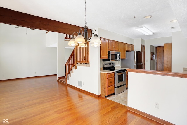 kitchen with a textured ceiling, decorative light fixtures, stainless steel appliances, light hardwood / wood-style floors, and a notable chandelier