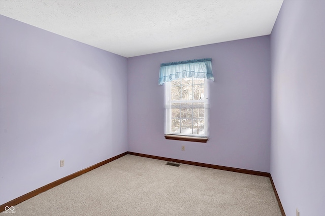 spare room featuring a textured ceiling and carpet