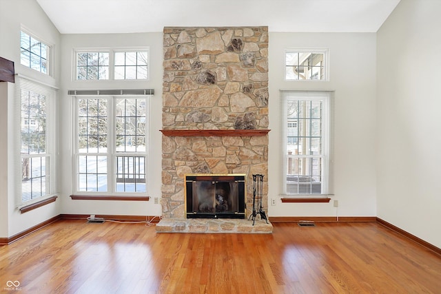 unfurnished living room featuring a fireplace, hardwood / wood-style floors, and a high ceiling