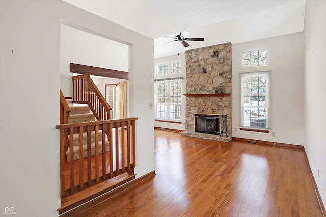 unfurnished living room with ceiling fan, a healthy amount of sunlight, a fireplace, and wood-type flooring