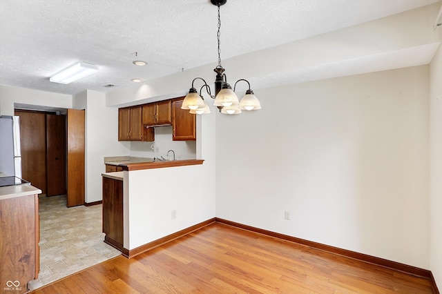 kitchen featuring decorative light fixtures, a textured ceiling, white refrigerator, and kitchen peninsula