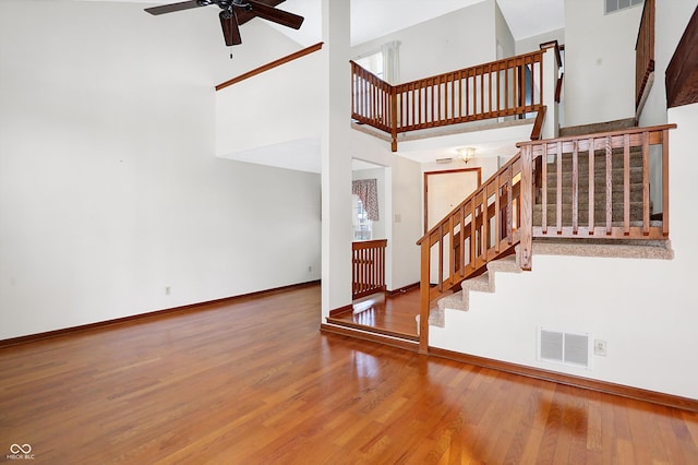 stairs featuring hardwood / wood-style flooring, a high ceiling, and ceiling fan