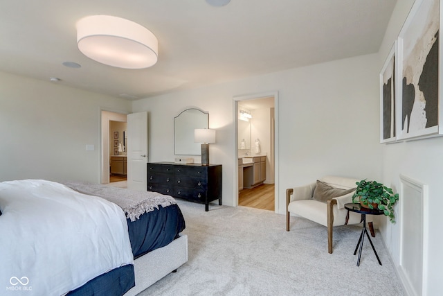 bedroom with ensuite bathroom and light colored carpet