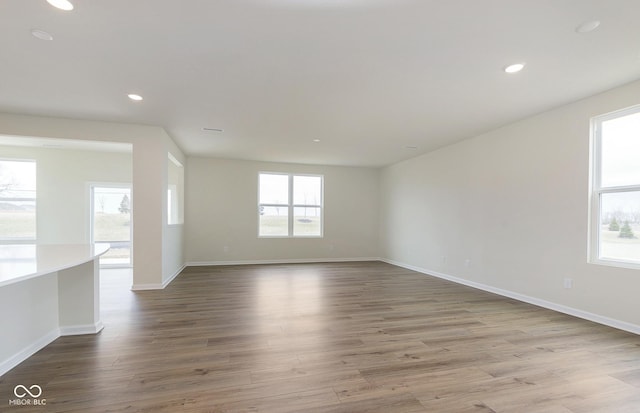 unfurnished room featuring baseboards, wood finished floors, and recessed lighting