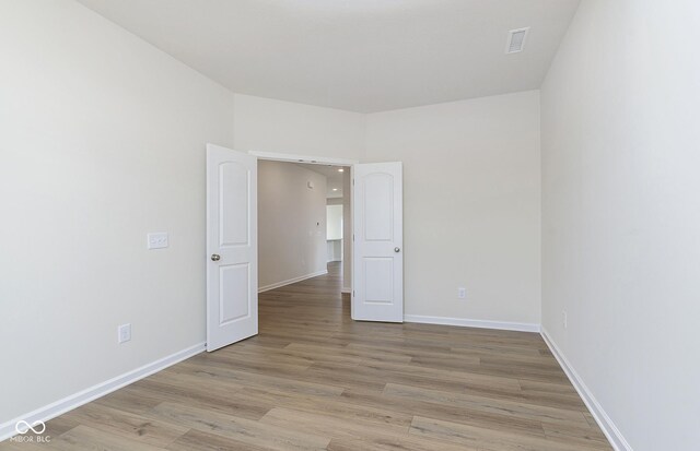 spare room featuring light wood-type flooring, visible vents, and baseboards