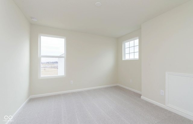 empty room featuring light carpet and baseboards