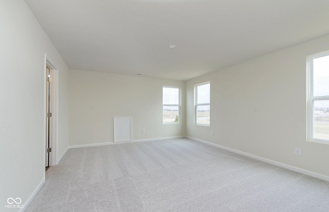 empty room featuring visible vents, light colored carpet, and baseboards