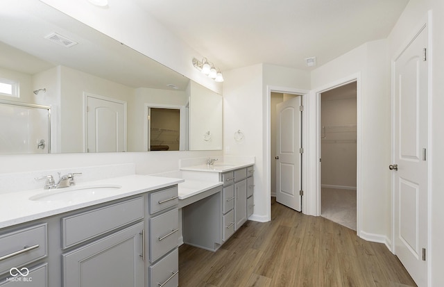 bathroom featuring visible vents, wood finished floors, a spacious closet, an enclosed shower, and vanity