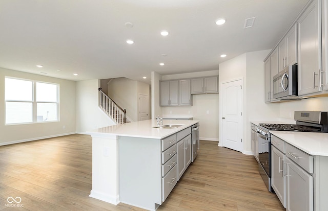 kitchen featuring light wood-style flooring, appliances with stainless steel finishes, gray cabinets, and recessed lighting