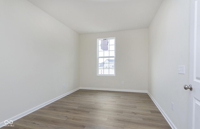 spare room with baseboards and wood finished floors