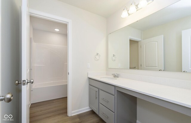 bathroom featuring tub / shower combination, vanity, baseboards, and wood finished floors