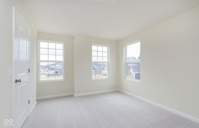 empty room featuring light colored carpet and baseboards