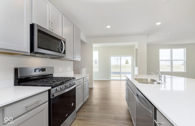 kitchen featuring appliances with stainless steel finishes, light wood-type flooring, light countertops, and a sink